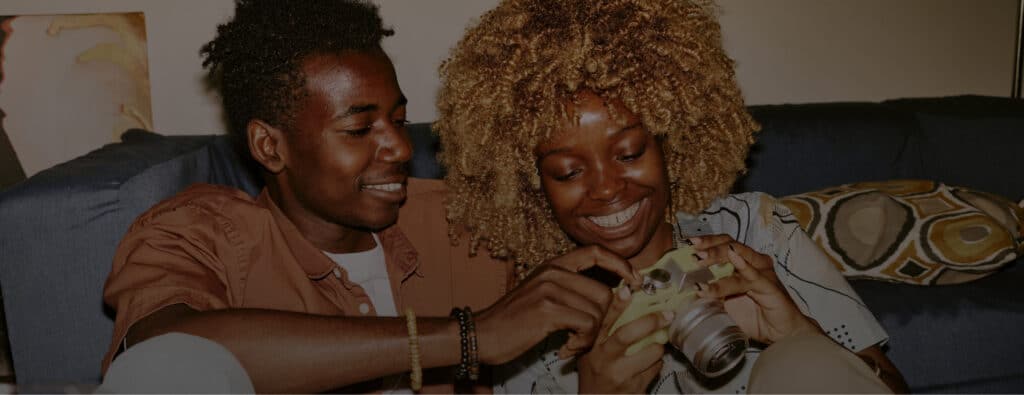 Two people smiling and looking at a bright yellow camera together