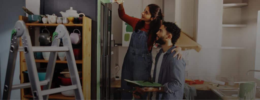 Couple painting kitchen cabinets together, representing home improvement