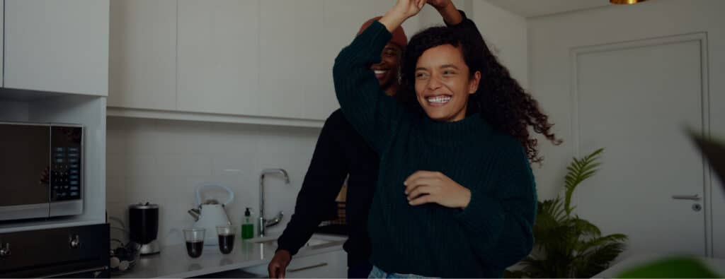 Two people smiling and dancing in a modern kitchen