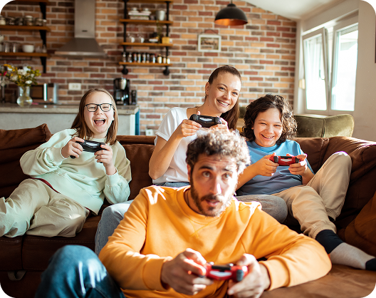 A happy family, two adults and two children, playing video games together in their living room