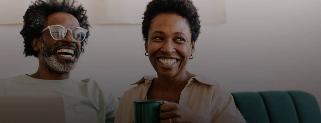 Two smiling adults, a man and a woman, laughing together