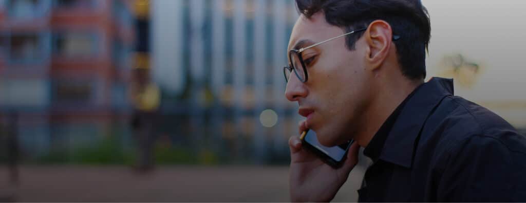 Man in glasses talks on a smartphone, blurred city background
