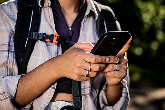Person wearing a backpack using a smartphone outdoors
