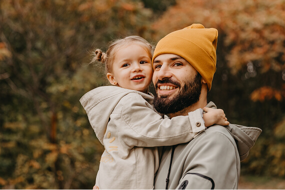 Smiling man holding a happy child against an autumn background