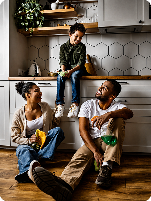 Smiling family with cleaning supplies taking a break from cleaning in their kitchen