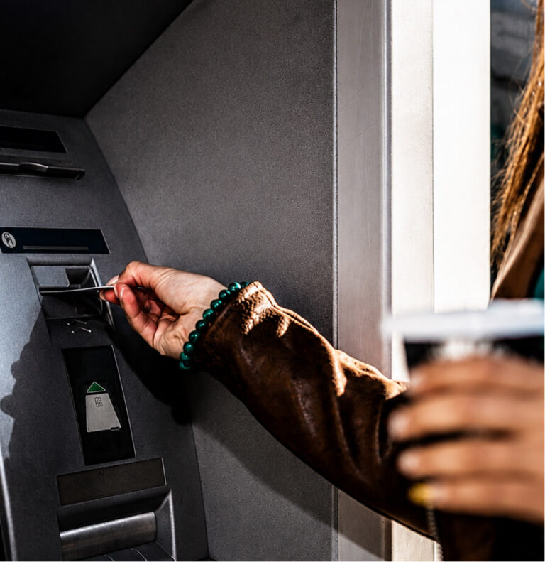 A person's hand inserting a bank card into an ATM