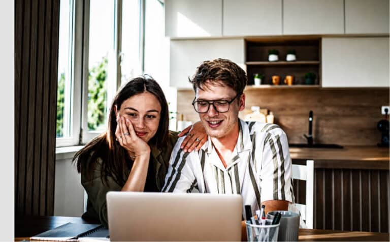 Couple smiling while looking at a laptop together