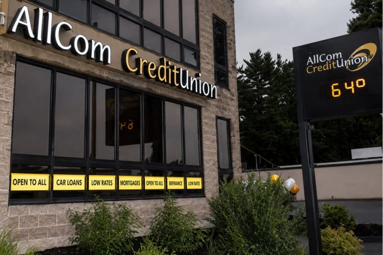 Exterior of AllCom CreditUnion building with signs for services like mortgages and car loans