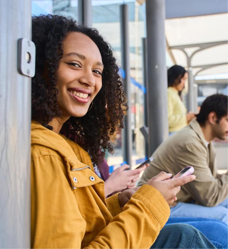 Smiling woman looks up from her phone while waiting with others