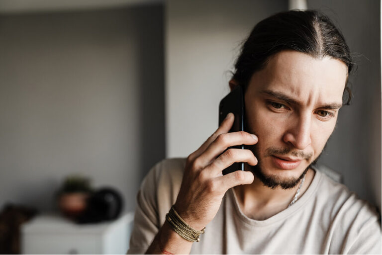 Man with concerned expression on phone, possibly reporting a lost or stolen item
