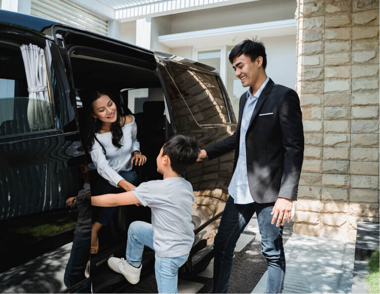 Man and woman helping a child climb into a black luxury van