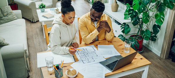 Two people reviewing home blueprints and financial documents at a table