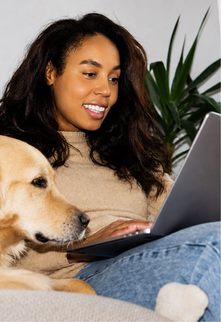 A smiling person and a golden retriever look at a laptop together