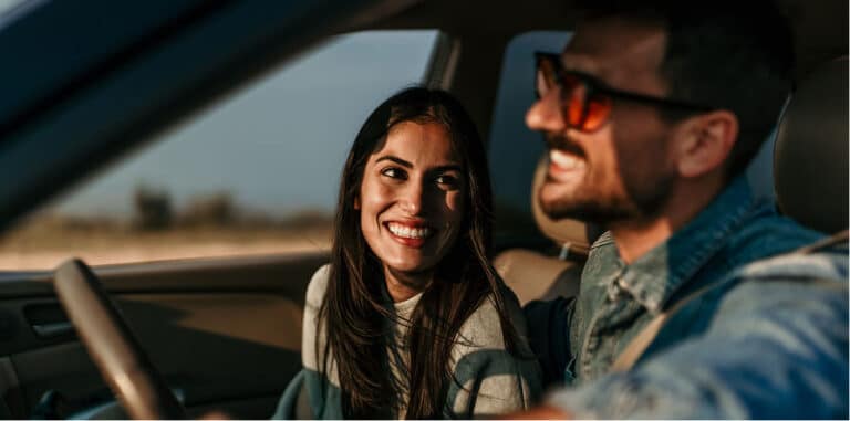 Smiling couple in a car enjoying a road trip or outing