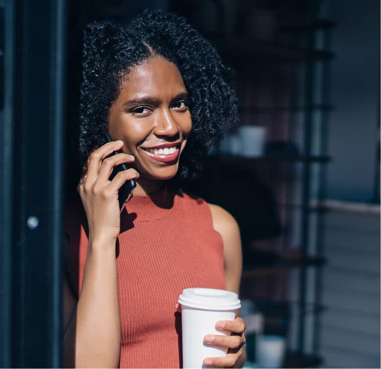 Smiling woman talking on phone and holding a coffee cup