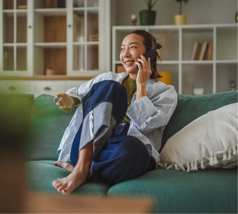 Woman smiles while talking on a mobile phone on a couch