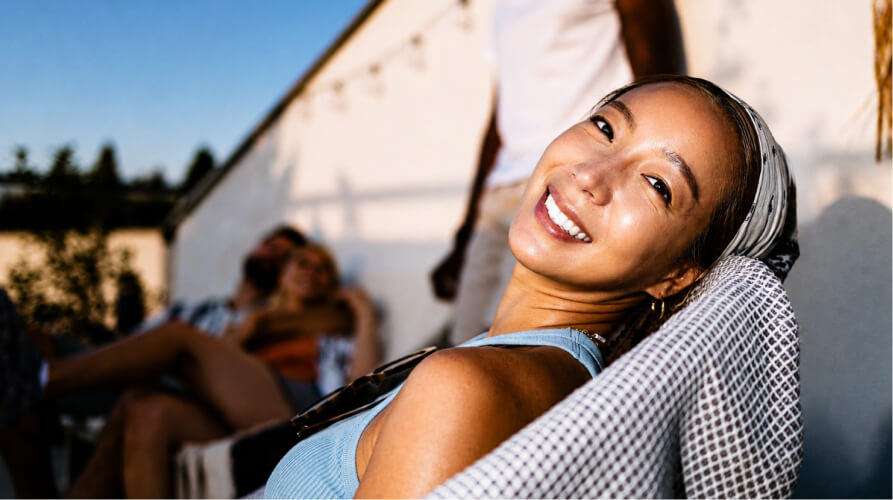 Smiling woman in a light blue top relaxing outdoors with friends