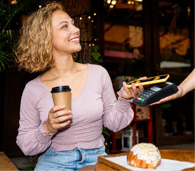 Woman paying contactless with her phone at a cafe