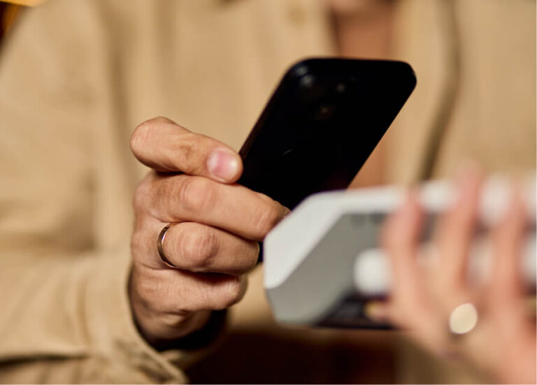 A person holding a smartphone near a payment terminal for a contactless transaction